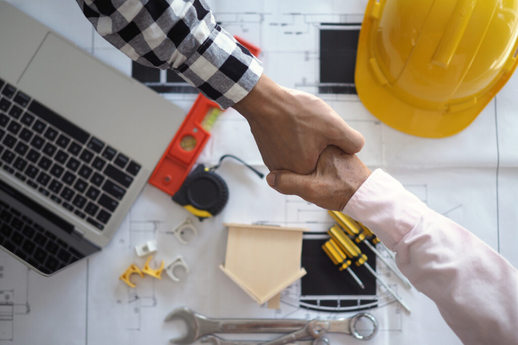 Como negociar com seus fornecedores: duas pessoas se cumprimentando sob papéis de projeto