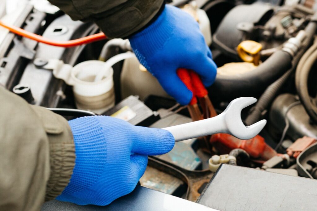 borracha EPDM: homem usando luvas de borracha para realizar conserto em carro