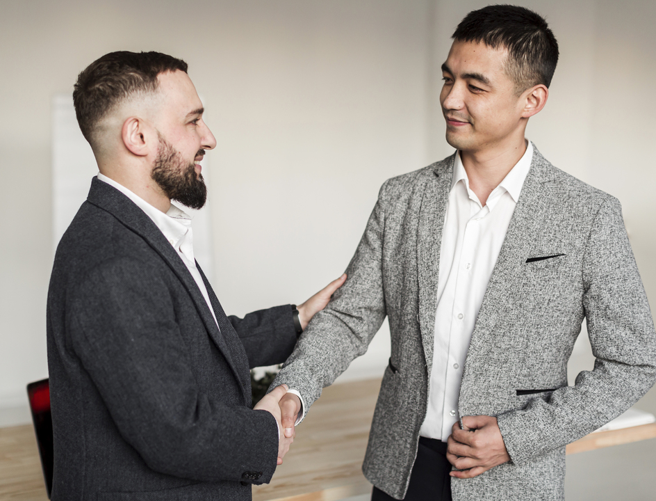 Dois homens de negócio apertando as mãos ao fazer um negócio lucrativo graças as técnicas de negociação em compras.