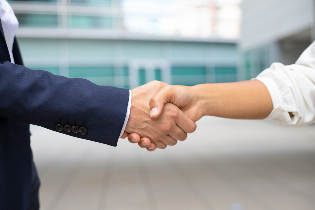 Um homem e uma mulher de negócios apertando as mãos depois de um acordo utilizando as técnicas de negociação.